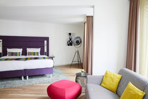 a bedroom with a large bed and a red stool at Hotel Indigo - Dusseldorf - Victoriaplatz by IHG in Düsseldorf
