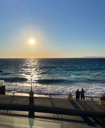 two people sitting on a pier looking at the ocean at Sunrise Luxury Apartments Rhodes in Rhodes Town