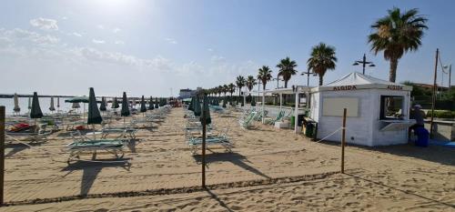 a sandy beach with chairs and umbrellas and a building at Lianna Beach Resort in Marina di Montenero