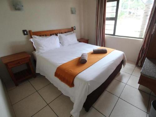 a bedroom with a bed with two towels on it at Pebble Beach in Uvongo Beach