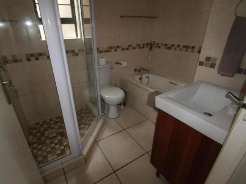 a bathroom with a toilet and a shower and a sink at Pebble Beach in Uvongo Beach