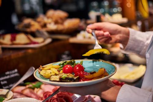 a person holding a plate of food on a table at Cocoon Sendlinger Tor in Munich