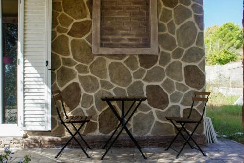 two chairs sitting in front of a stone wall at Anna Studios in Marathias