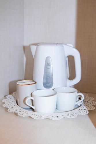 a white tea pot and cups on a table at Easy Milano - Rooms and Apartments Navigli in Milan