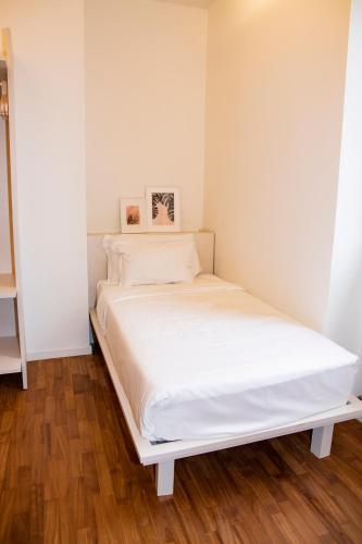 a bed in a room with white walls and wooden floors at Easy Milano - Rooms and Apartments Navigli in Milan