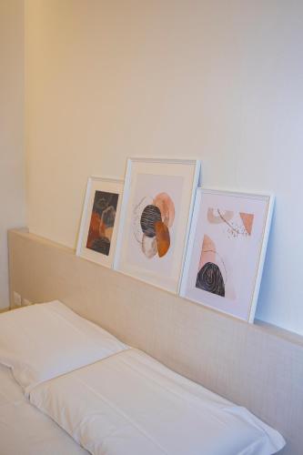 a shelf with four pictures on top of a bed at Easy Milano - Rooms and Apartments Navigli in Milan