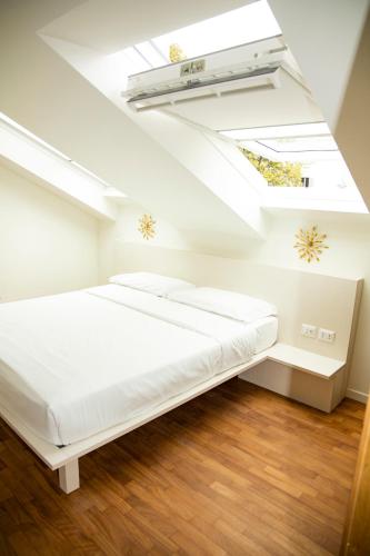 a white bedroom with a bed and a skylight at Easy Milano - Rooms and Apartments Navigli in Milan