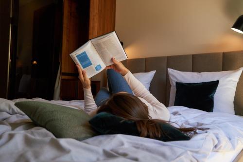 a woman laying on a bed reading a book at Cocoon Sendlinger Tor in Munich