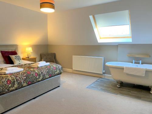 Schlafzimmer mit einem Bett, einer Badewanne und einem Fenster in der Unterkunft Rose Cottage with Hot Tub in Cray