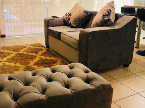 a couch and a ottoman in a living room at The Midlands Hotel in Pietermaritzburg