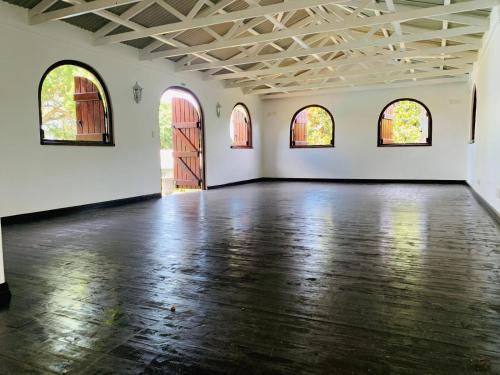 an empty room with a wooden floor and three windows at The Midlands Hotel in Pietermaritzburg