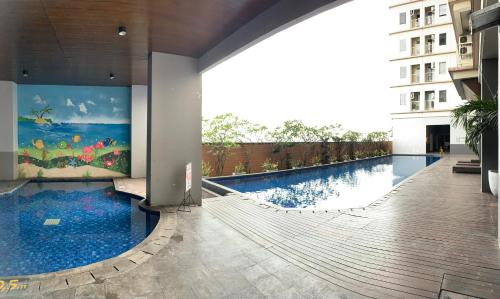 a swimming pool in a building with a painting on the wall at Apartemen Mahogany By Ruang Sultan in Karawang