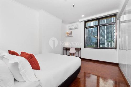 a white bedroom with a bed and a window at VEGA by Kozystay 3BR SCBD in Jakarta