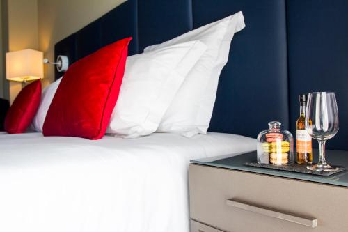 a bed with red and white pillows and a table with wine glasses at Melia Setubal in Setúbal