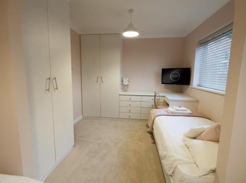 a bedroom with two beds and a tv on the wall at The Masters by STAMP SA in Lytham St Annes