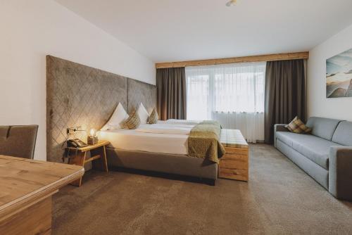 a hotel room with a bed and a couch at Der Gollinger in Saalbach Hinterglemm