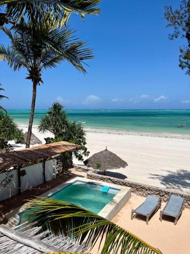 a swimming pool next to a beach with two chairs at Villa Lala in Kiwengwa