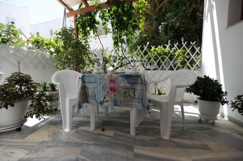 a white table and chairs on a patio with plants at Marisa Rooms in Parikia
