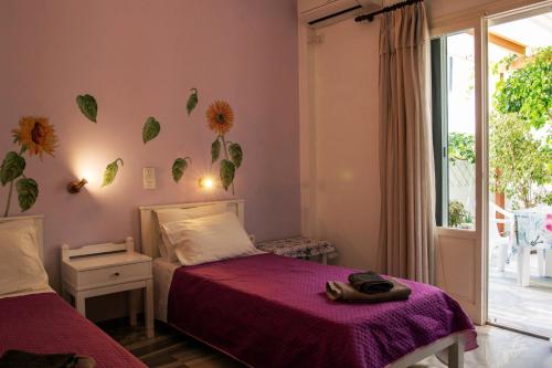 a bedroom with two beds with purple sheets and a window at Marisa Rooms in Parikia
