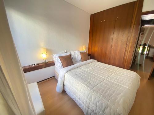 a bedroom with a white bed and two lamps at Amazing Tróia in Troia