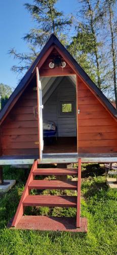 a red cabin with stairs leading to a door at SZAŁASY drewniane nad rzeką BIEBRZA in Goniadz