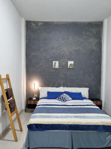 a bedroom with a blue and white bed and a wall at Choko Guest House in Solo