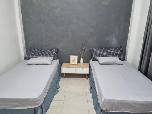 two twin beds in a room with a table at Choko Guest House in Solo