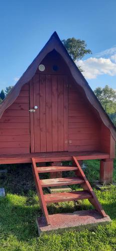 a red doghouse with a door on top of it at SZAŁASY drewniane nad rzeką BIEBRZA in Goniadz