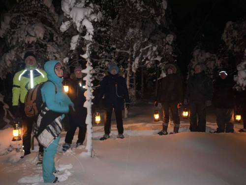 a group of people standing in the snow at night at Uuejärve house at Kõrvemaa forest in Pillapalu
