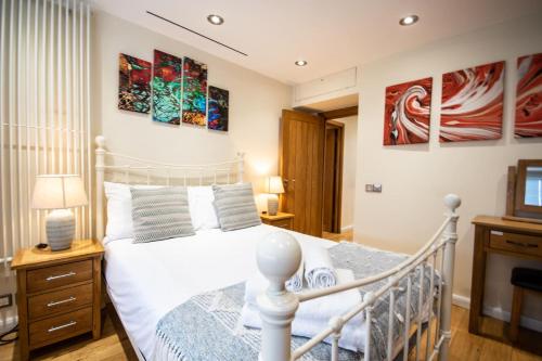 een slaapkamer met een wit bed en schilderijen aan de muur bij Tower Bridge 2BR apartment for 6 with terrace in Londen