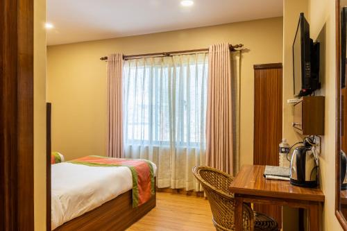 Habitación de hotel con cama, escritorio y ventana en Kuna Resort, en Katmandú