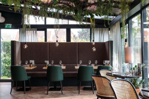 a dining room with a long table with green chairs at Hotel 't Paviljoen in Rhenen