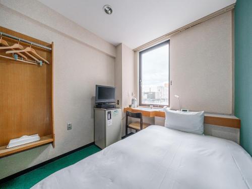 ein Hotelzimmer mit einem großen Bett und einem TV in der Unterkunft Tabist THE GREEN OTARU in Otaru