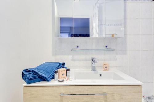 a white bathroom with a sink and a mirror at Charmant T2 proche de Disney in Noisy-le-Grand
