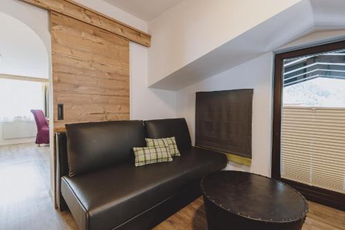 a black leather couch in a living room with a table at Der Gollinger in Saalbach Hinterglemm