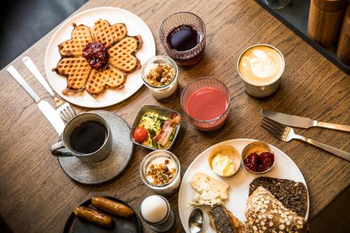 a wooden table topped with plates of food and drinks at Hotel Kong Arthur in Copenhagen