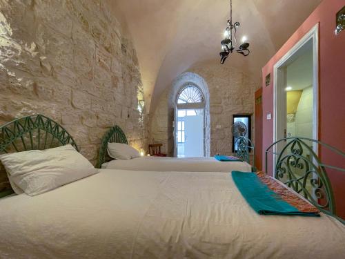a bedroom with two beds and a stone wall at Dar al Majus in Bethlehem