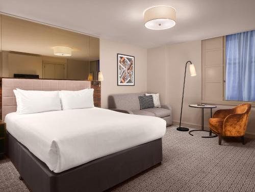 Pokój hotelowy z dużym łóżkiem i krzesłem w obiekcie Strand Palace Hotel w Londynie