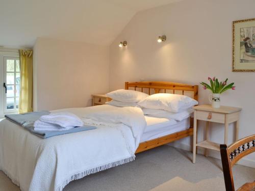 a bedroom with a bed with white sheets and pillows at Bridge End Cottage in Cregrina