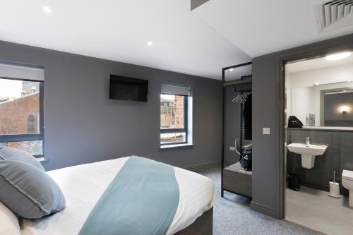 een slaapkamer met een bed en een badkamer met een wastafel bij Bank Square Town House in Belfast