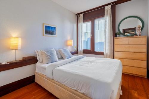 a bedroom with a large white bed with a window at Apartamento Troia in Troia