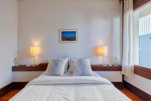a bedroom with a bed with two lamps and a window at Apartamento Troia in Troia