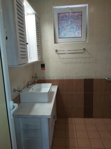 a bathroom with a white sink and a window at Galaxy Hotel in Chiflik