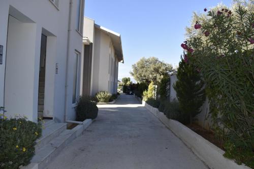 an empty alley between two white buildings with flowers at Memories Signature Apartment in Cedit