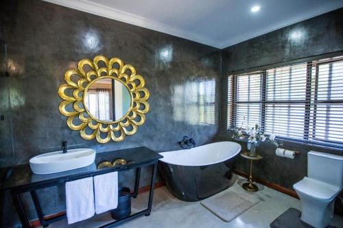 La salle de bains est pourvue d'une baignoire, d'un lavabo et d'un miroir. dans l'établissement The Bohemian Guesthouse, à Tzaneen