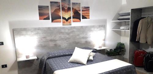 una camera da letto con un letto con due lampade e immagini appese al muro di SHORT LETS Radici di Puglia a Fragagnano