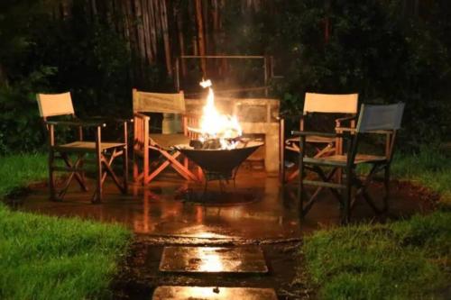 miejsce na ognisko na dziedzińcu z krzesłami i stołem w obiekcie Dwardos Cottage - Serene Private Cottage w/Wi-Fi w mieście Nyeri