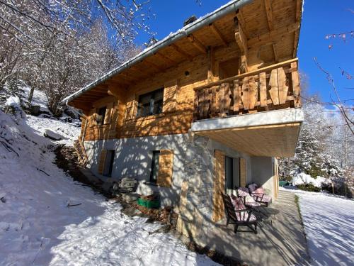 a log cabin in the snow with chairs on the porch at Chalet 7 Luxury Chalet with Cinema room in Crans-Montana