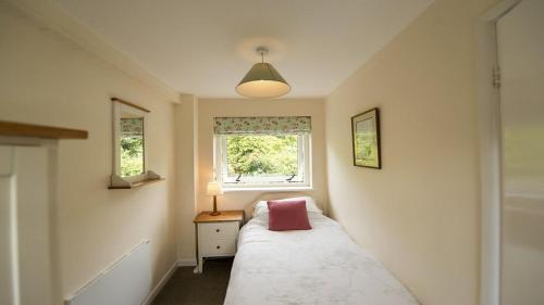 a small bedroom with a bed and a window at The Pack Horse Exmoor National Park Allerford Riverside Cottage & Apartments in Minehead