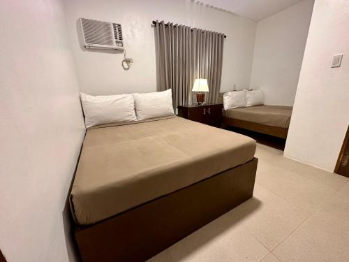Una habitación de hotel con dos camas y una ventana. en The Resthouse Laiya, en Batangas
